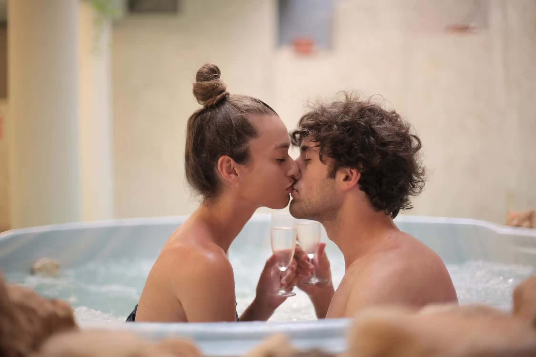 Couple amoureux dans un spa privatif avec deux coupes de champagne