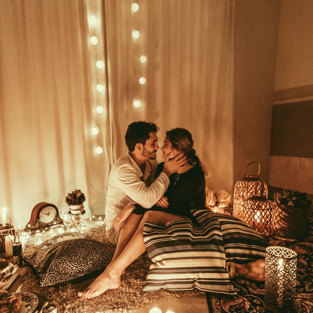 Soirée sensuelle dans un cocon lumineux, couple enlacé dans une ambiance romantique à la maison.