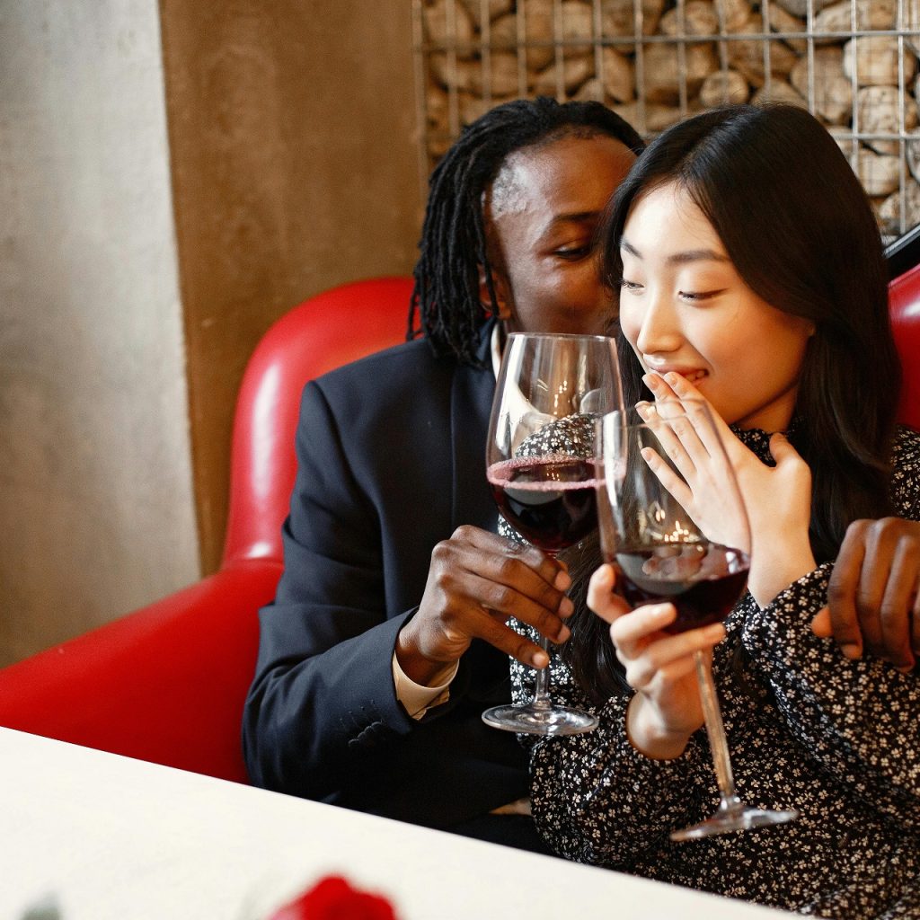 Soirée sensuelle en tête-à-tête au restaurant, complicité et rires autour d’un verre de vin.
