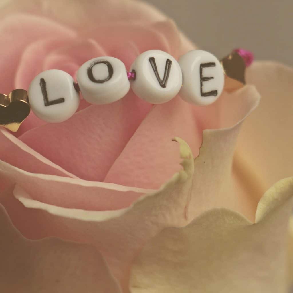Bracelet avec le mot LOVE posé sur une rose, symbole d’amour et de romantisme dans une love room à Toulouse.
