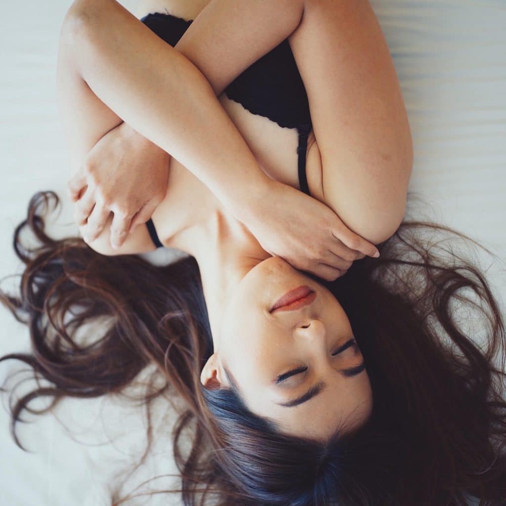 Femme allongée en lingerie sur un lit blanc, ambiance romantique – en week-end amoureux à Toulouse
