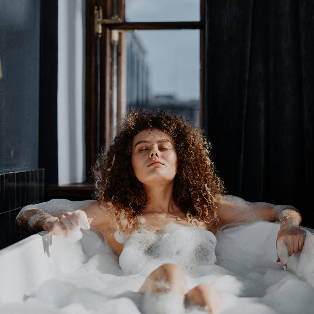 Love room vs hôtel romantique Toulouse : Femme profitant d’un bain moussant dans une baignoire d’hôtel romantique à Toulouse, atmosphère relaxante.
