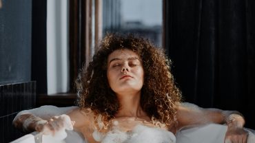 Love room vs hôtel romantique Toulouse : Femme profitant d’un bain moussant dans une baignoire d’hôtel romantique à Toulouse, atmosphère relaxante.