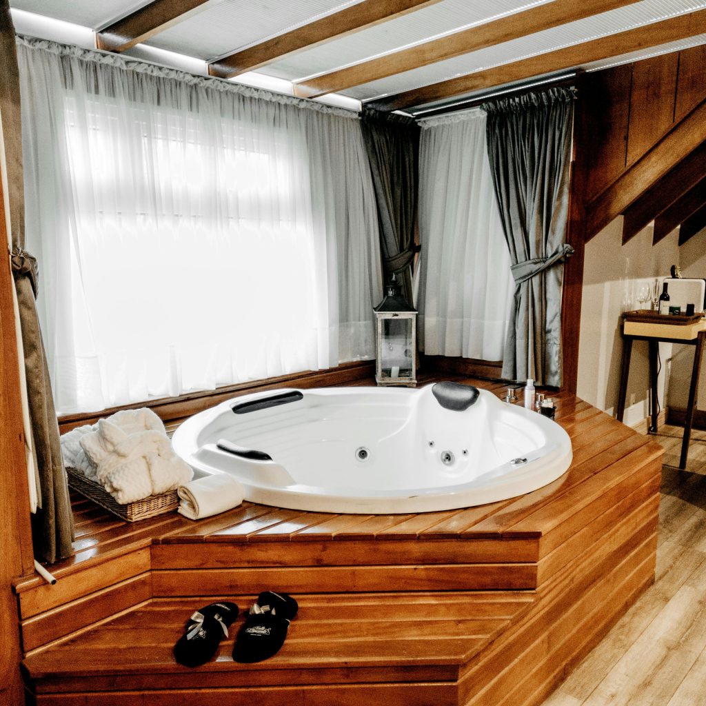 Suite romantique avec jacuzzi privatif en bois dans une love room à Toulouse, idéale pour un week-end en amoureux.