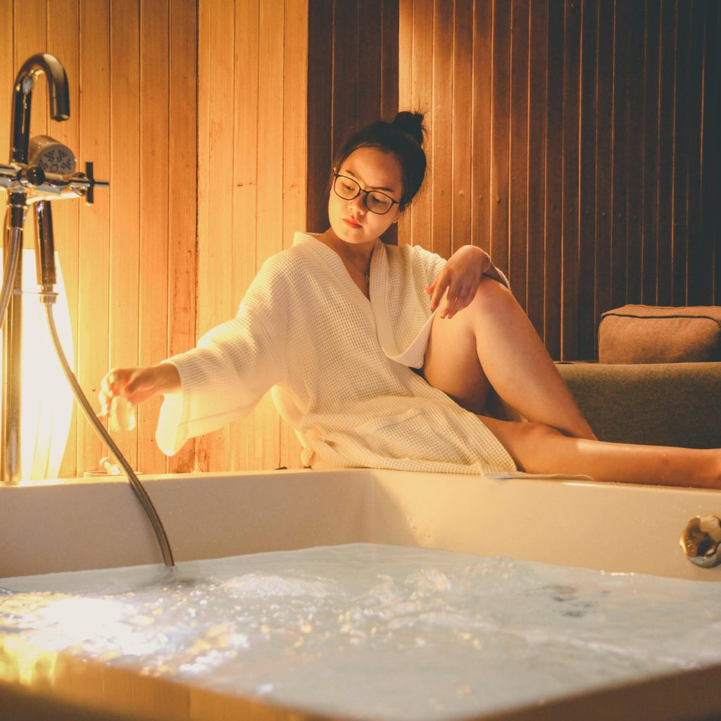 Femme en peignoir se relaxant dans une baignoire de love room Toulouse jacuzzi