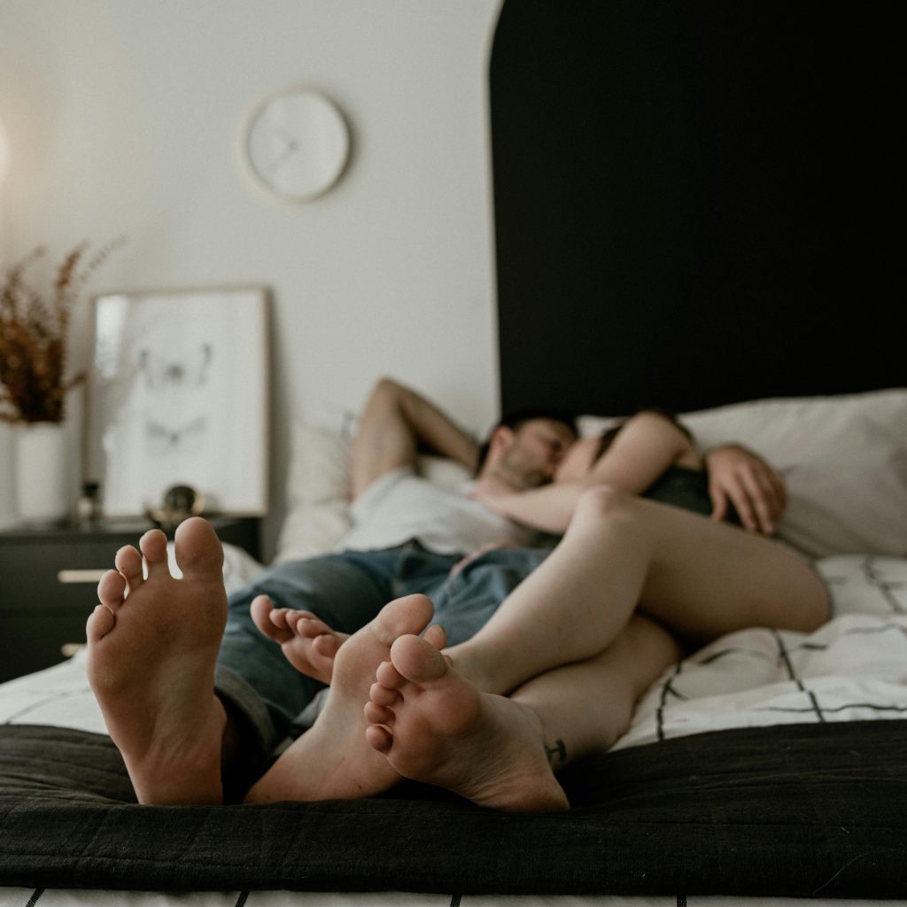 Couple allongé sur un lit dans une chambre confortable, moment de détente lors d’une nuit romantique en Love room Toulouse.