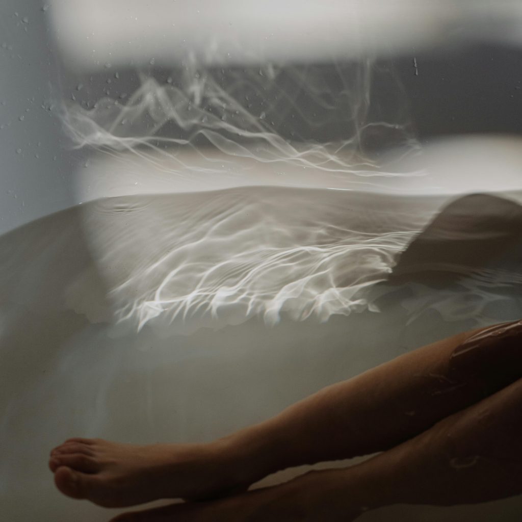 Pieds immergés dans une baignoire d’une love room Bretagne avec spa privatif intimiste