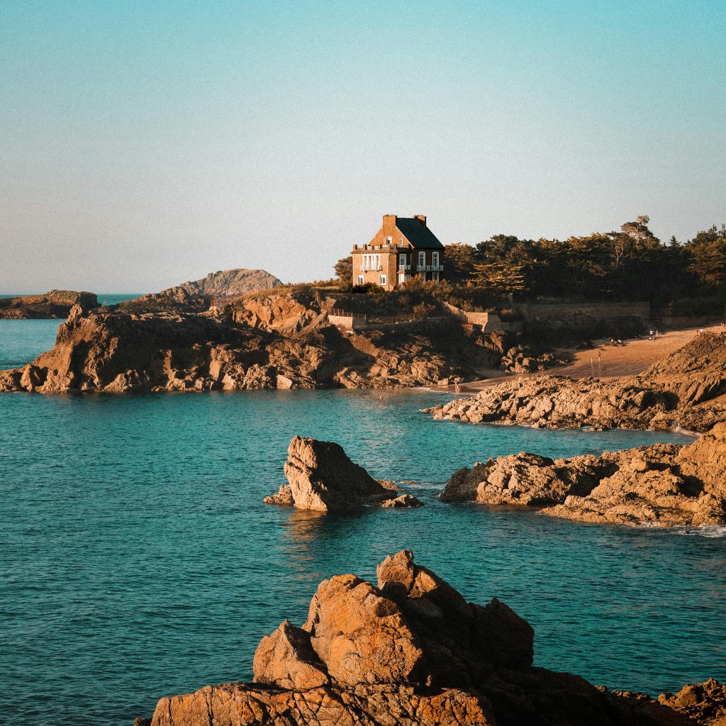 Maison située sur un rocher en pleine mer, illustrant le concept d'une escapade romantique isolée et unique.