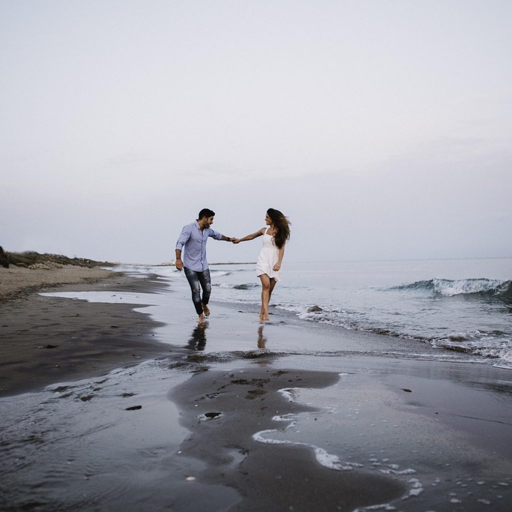 Couple amoureux courant sur la plage en Corse, après une journée de love room Corse randonnée en bord de mer